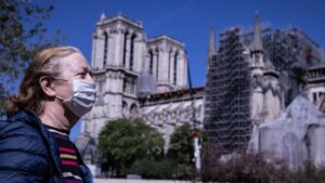 Una mujer con mascarilla pasa por delante de Notre Dame coronavirus francia
