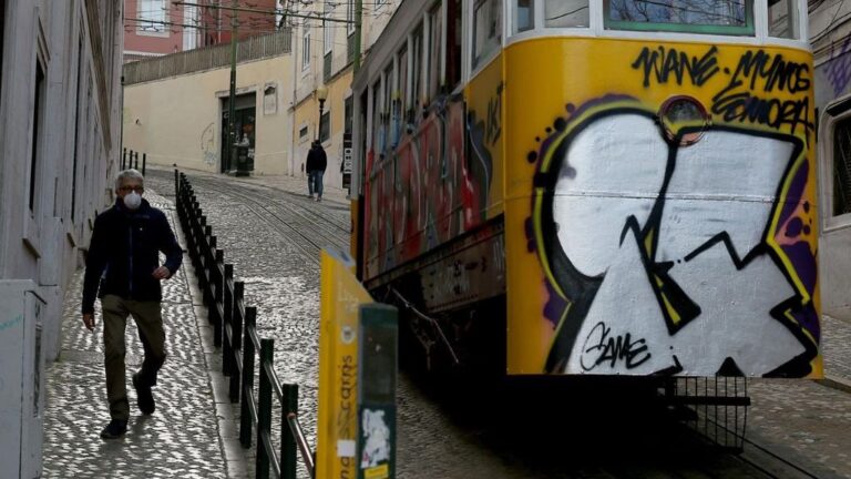 Un hombre con mascarilla junto a un tranvía de Lisboa