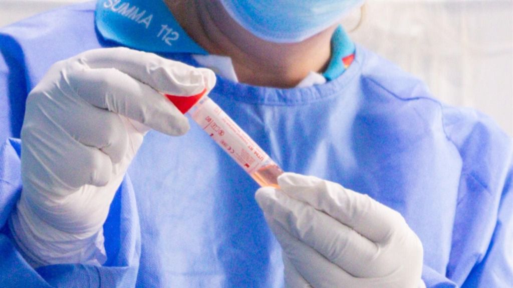 Un trabajador sanitario protegido sostiene una de las probetas utilizadas para la realización de tests PCR