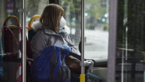 Una mujer con mascarilla en un autobús urbano