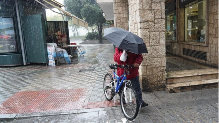 Un ciclista con un pagaguas resguardándose de la lluvia y el viento