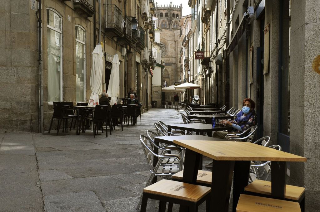 Una mujer permanece sentada en una terraza del barrio de O Coutoen Ourense