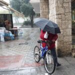 Un ciclista con un pagaguas resguardándose de la lluvia y el viento