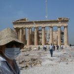 Una mujer con mascarilla frente al Partenón de Atenas