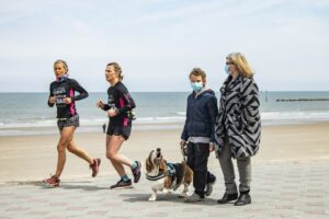 Dos mujeres corren por la playa mientras que una mujer y un niño pasean un perro en una imagen de archivo de las playas de Dunkerque