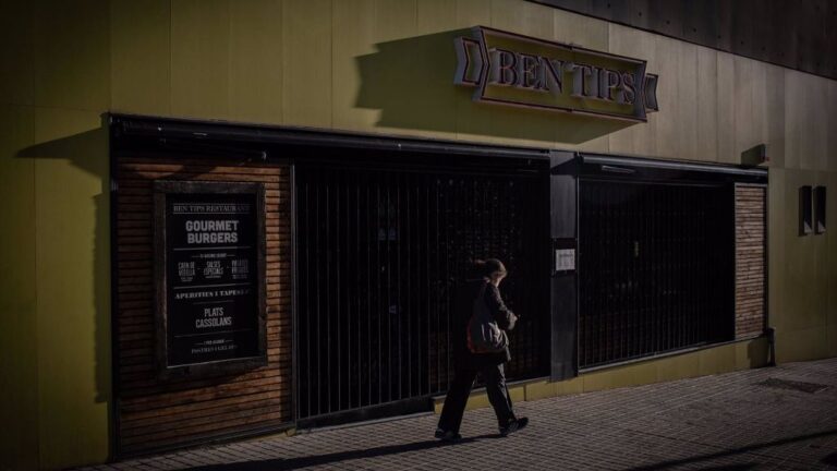 Un hombre pasa por un bar cerrado en Barcelona.