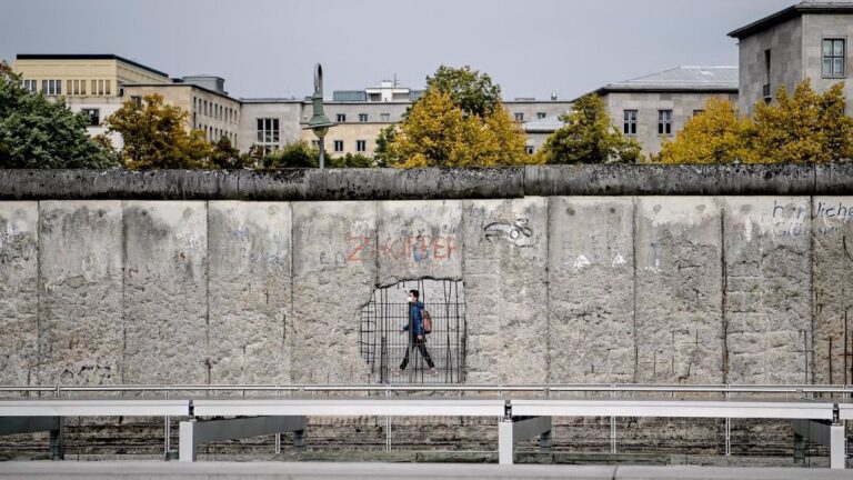 Un hombre con mascarilla pasando ante un muro de un museo en Niederkirchnerstrasse, en Berlín alemania coronavirus