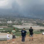 Cuatro vecinos observan desde un alto el avance de la colada de lava del volcán de La Palma en las cercanías de la localidad de La Laguna. EFE / Carlos de Saa