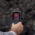 Un hombre mide la temperatura de una colada de lava, en la zona de exclusión próxima al volcán de Cumbre Vieja. - Alexandre Diaz - Europa Press