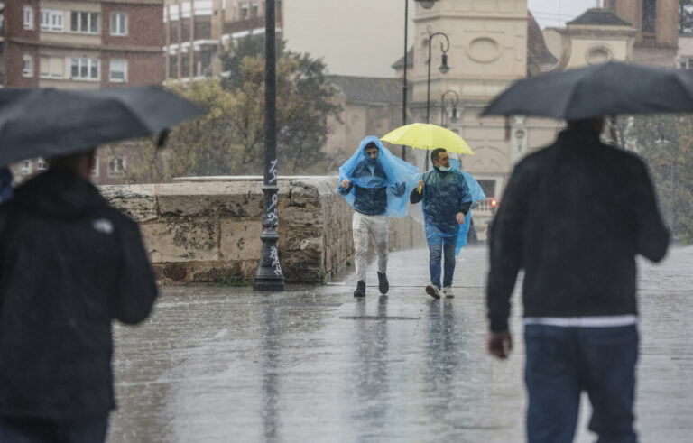 Dos personas con paraguas y chubasqueros caminan bajo la lluvia, a 3 de mayo de 2022, en València. - Rober Solsona - Europa Press