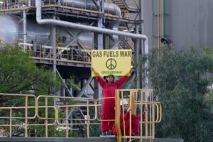 Una activista de Greenpeace en una central térmica de Málaga en una acción de protesta por el uso de gas ruso - GREENPEACE