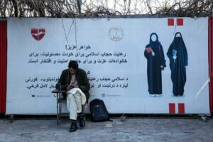 Un alumno de la Universidad privada de Rana sentado junto a un cartel con un mensaje sobre el código de vestimenta para las estudiantes. Las universidades afganas reabrieron el 6 de marzo, pero solo los hombres pudieron volver a clase debido a la prohibición de los talibanes. / EFE /EPA /SAMIULLAH POPAL