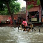 Joven con discapacidad se desplaza en una calle inundada | Foto de Mukesh Kumar Jwala/Shutterstock