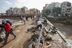 Decenas de voluntarios trabajan para despejar uno de los puentes de Paiporta, Valencia, este lunes. / EFE | Manuel Bruque