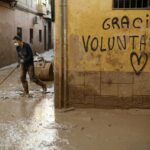 Un voluntario retira fango de una calle de Paiporta (Valencia) este jueves. / EFE/ Biel Aliño