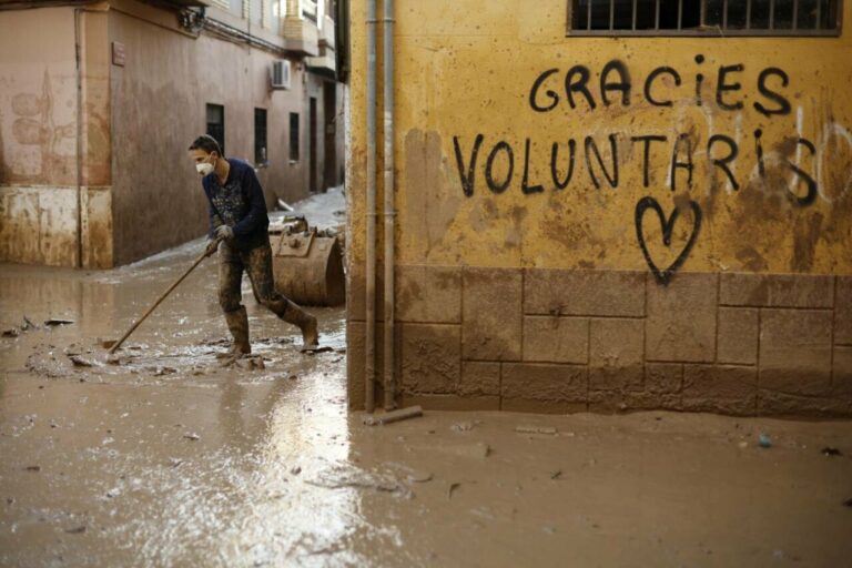 Un voluntario retira fango de una calle de Paiporta (Valencia) este jueves. / EFE/ Biel Aliño