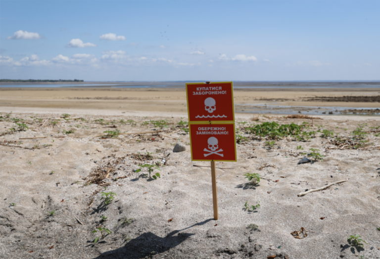 El antiguo fondo del embalse de Kakhovka el 25 de junio de 2023, después de la voladura de la presa que lo vació. Los carteles prohíben nadar y advierten de la presencia de minas. / Ivan Antipenko