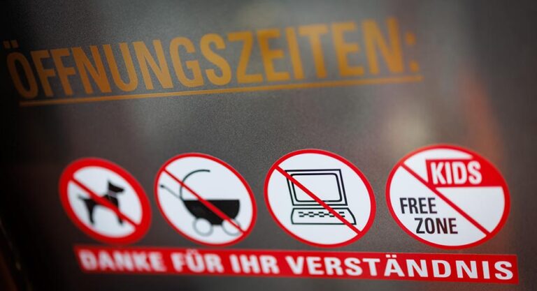 Un cartel en la cafetería "8tto Grammi", de la ciudad alemana de Bayreuth, donde se especifica la prohibición del uso de ordenadores portátiles, a la par que la presencia de perros, carritos de bebé y zona de juegos para niños ("¿Por qué cada vez más cafeterías alemanas prohíben uso de portátiles?"). (Foto: Daniel Karmann/dpa)