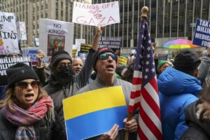 Una persona sostiene una bandera estadounidense y una ucraniana frente a la sede de Fox News en Nueva York, este 4 de marzo de 2025, durante una protesta organizada por el grupo activista Rise and Resist. EFE/EPA/SARAH YENESEL