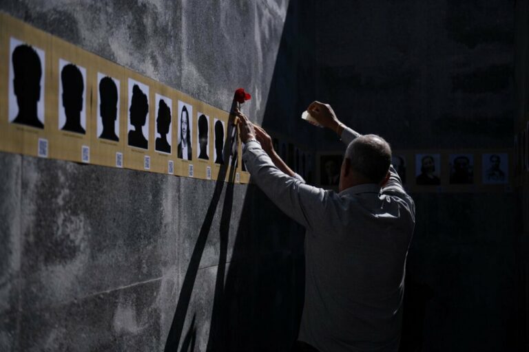 Un hombre coloca un clavel en la foto de una víctima durante el XVII Homenaje a las víctimas del franquismo en Madrid (Foto: Fernando Sánchez - Europa Press)