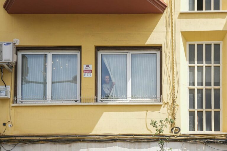 Una mujer asomada a la ventana de la casa del exministro de Transportes José Luis Ábalos durante un registro por parte de la UCO, a 10 de junio de 2025, en Valencia, Comunidad Valenciana (España). - Jorge Gil - Europa Press