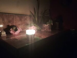 Mesa con plantas y una vela encendida en un ambiente oscuro. Apagones en Cuba