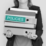 Mujer sosteniendo carpetas con la etiqueta Policies