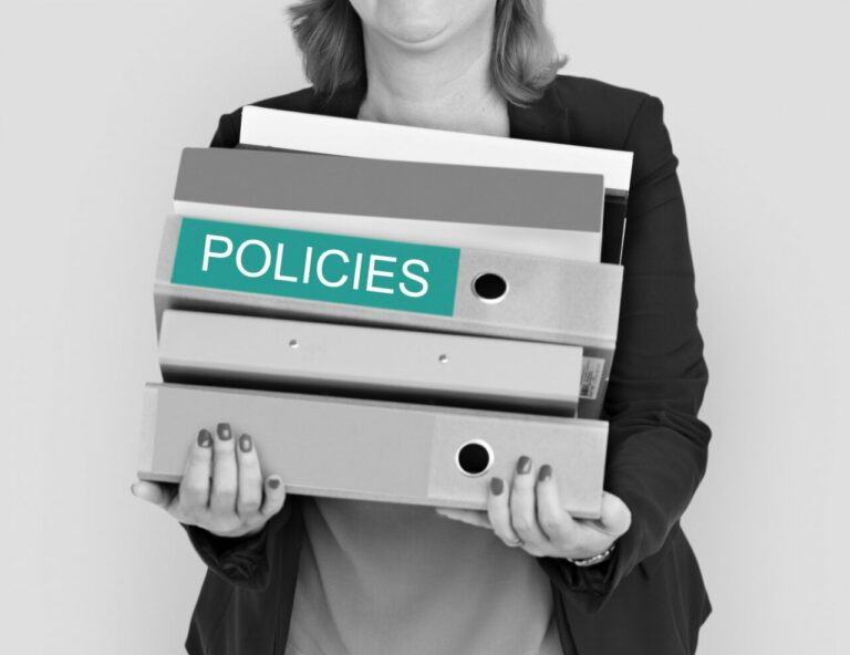 Mujer sosteniendo carpetas con la etiqueta Policies