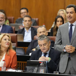 Juan Manuel Moreno hablando en el Parlamento de Andalucía con otros asistentes