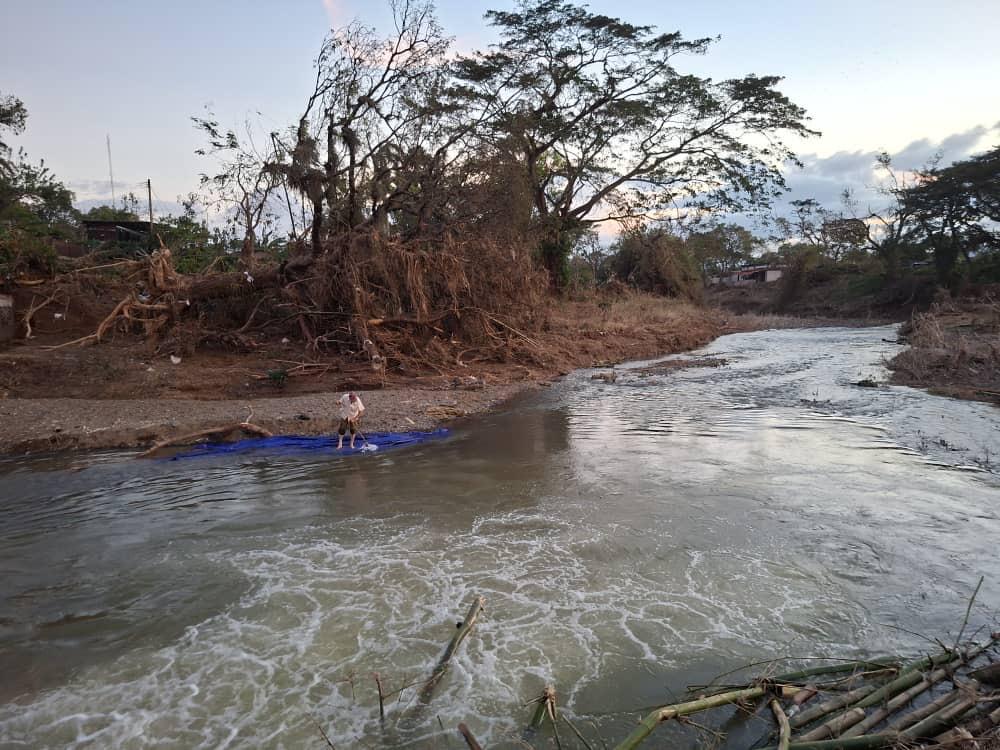 La imagen muestra el impacto del huracán Melissa en un río en Cuba, con árboles caídos y una persona en la orilla. Este desastre ha destruido más de 45,000 viviendas y dejado a 120,000 personas evacuadas. La respuesta humanitaria es vital para ayudar a las comunidades afectadas y restaurar la normalidad en la región (Foto: Julio A. Larramendi)