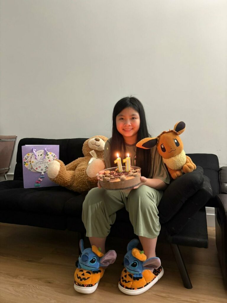 Niña con pastel de cumpleaños y juguetes en un sofá