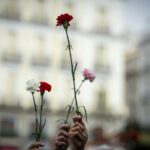 Varias personas sujetan flores durante una manifestación de Marea de Residencias (Foto: Juan Barbosa - Europa Press)