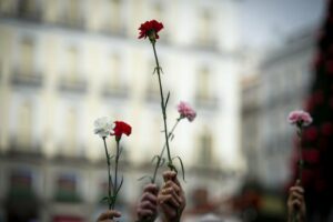 Varias personas sujetan flores durante una manifestación de Marea de Residencias (Foto: Juan Barbosa - Europa Press)
