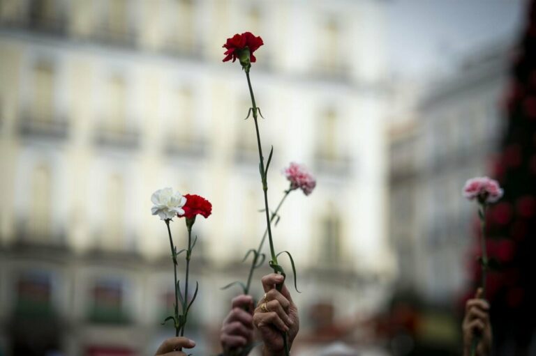 Varias personas sujetan flores durante una manifestación de Marea de Residencias (Foto: Juan Barbosa - Europa Press)