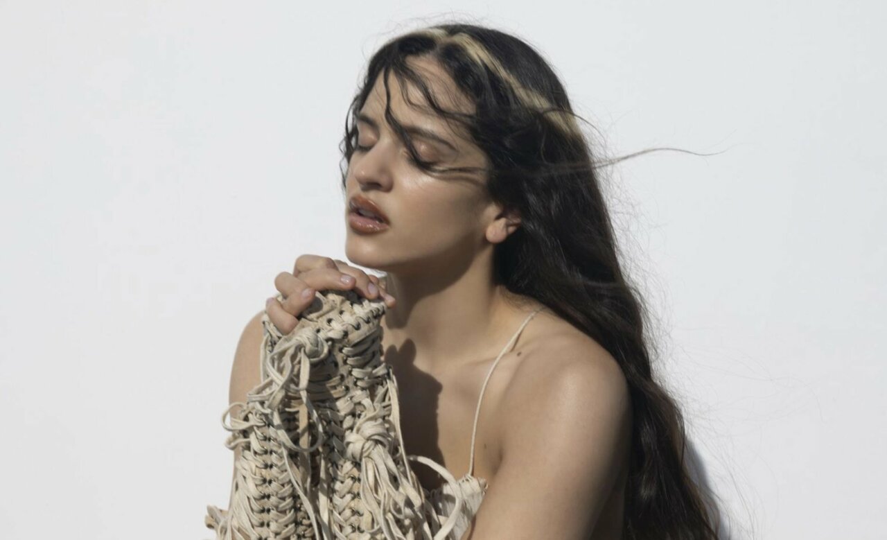 Rosalía con cabello largo y prenda de diseño en fondo blanco