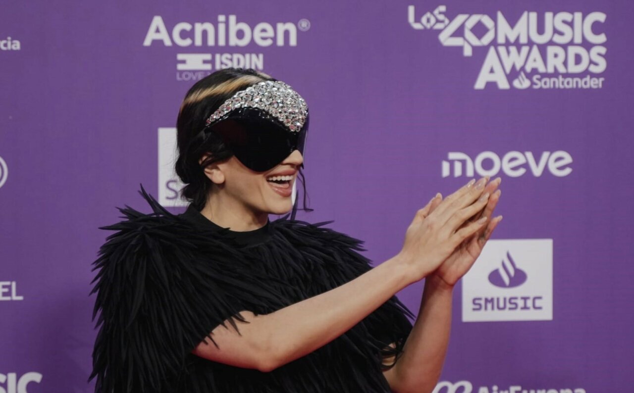 Rosalía en la alfombra roja de un evento musical con un atuendo llamativo.