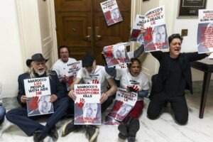 Protesta contra recortes en la lucha contra el VIH con carteles en manos.