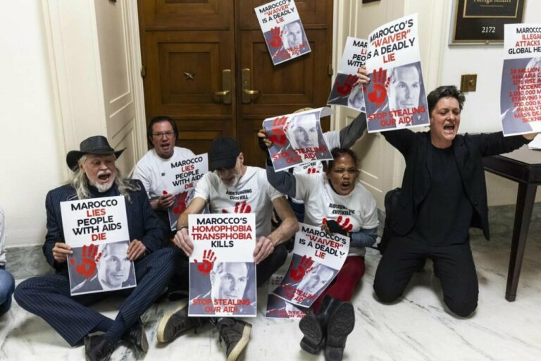Protesta contra recortes en la lucha contra el VIH con carteles en manos.