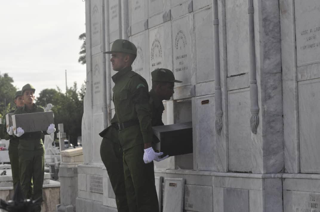 Ceremonia f&uacute;nebre con soldados llevando un ata&uacute;d en un cementerio.