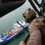 Militares observando un petrolero desde un helic&oacute;ptero en el mar