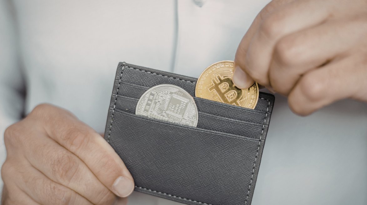 Persona sosteniendo una cartera con monedas de criptomonedas