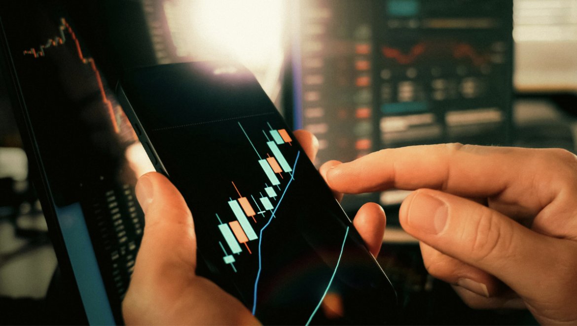 Persona interactuando con gr&aacute;ficos de cotizaciones en un smartphone