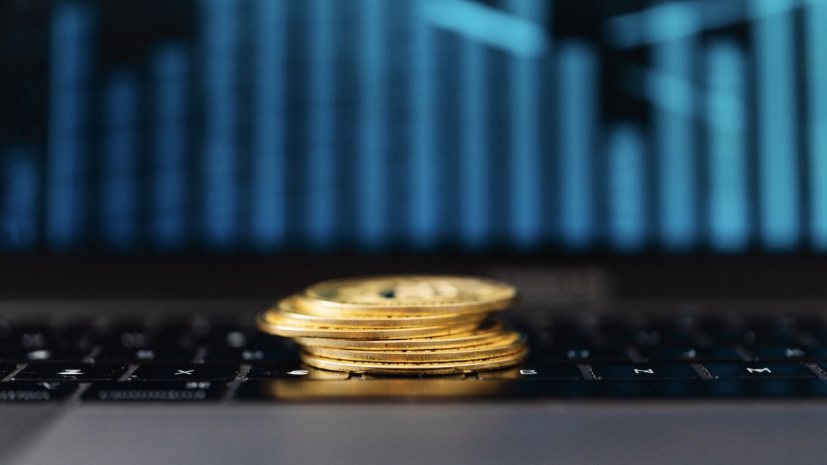 Mont&oacute;n de monedas digitales sobre un teclado de laptop