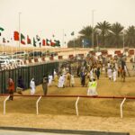 Camellos en una carrera en Oriente Medio con espectadores y banderas