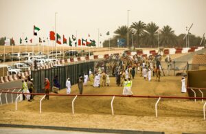 Camellos en una carrera en Oriente Medio con espectadores y banderas
