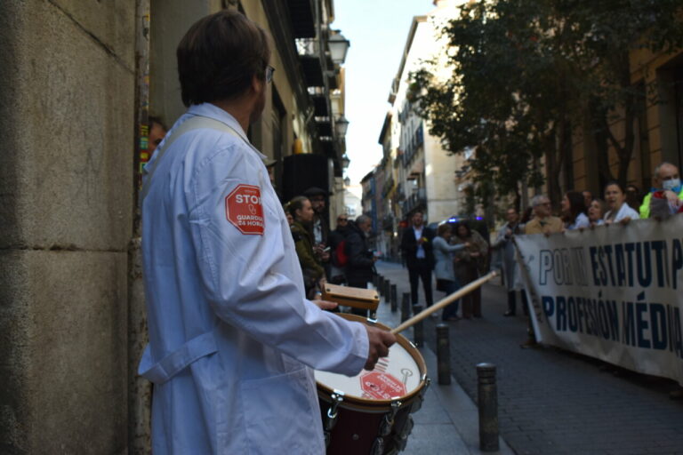 M&eacute;dico con bata blanca tocando un tambor en una manifestaci&oacute;n