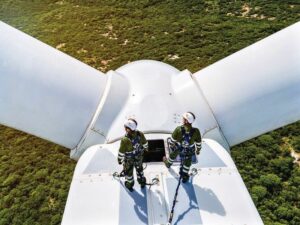 Dos trabajadores en la cima de un aerogenerador observando el paisaje