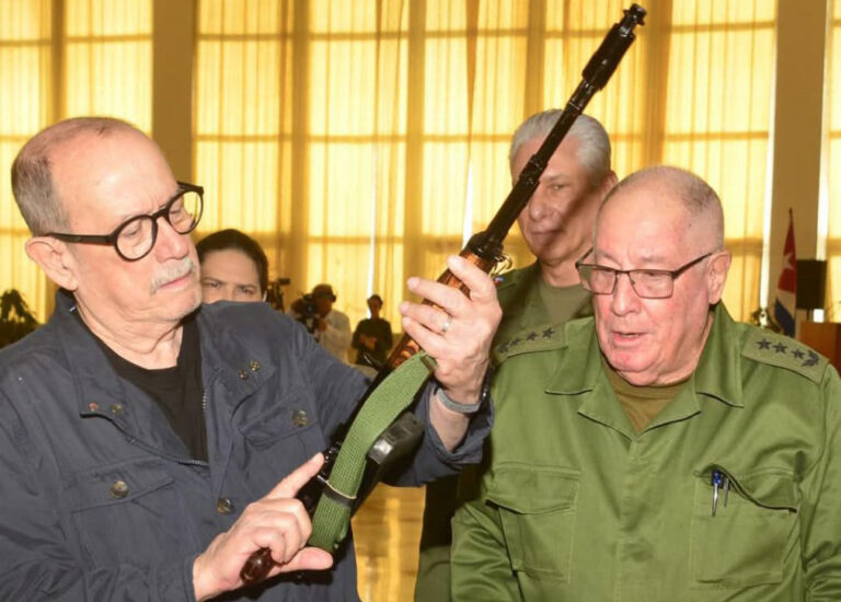 Silvio Rodr&iacute;guez sosteniendo un fusil durante una ceremonia en Cuba.