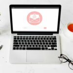 Port&aacute;til abierto mostrando una interfaz de email marketing con una taza de t&eacute;