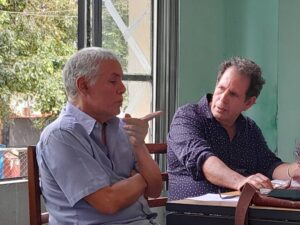 Dos hombres conversando en un evento literario sobre poes&iacute;a.